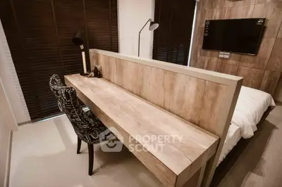 Modern bedroom with stylish desk and wall-mounted TV, featuring elegant decor and natural light.