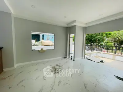 Spacious modern living room with marble flooring and large windows opening to a balcony with lush views.