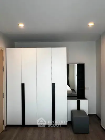 Modern bedroom with sleek wardrobe and stylish vanity in a contemporary apartment.