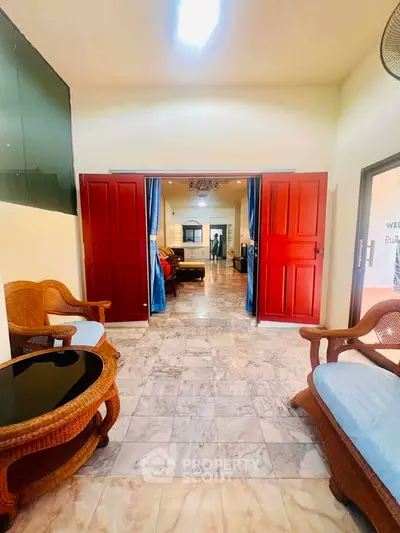 Spacious living area with elegant marble flooring and stylish wicker furniture, leading to a cozy interior.