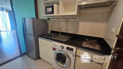 Modern compact kitchen with washing machine and fridge in open layout apartment