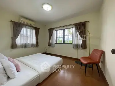 Cozy bedroom with natural light, wooden flooring, and modern decor.