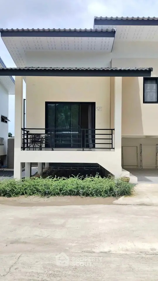 Modern two-story house with balcony and sleek exterior design.
