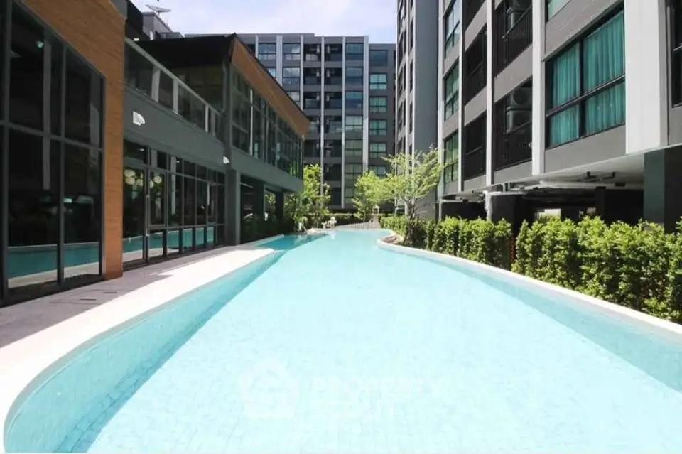 Luxurious modern apartment complex with a stunning outdoor pool and lush greenery, perfect for relaxation.