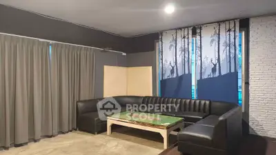 Spacious living room with modern sectional sofa and unique forest-themed window shades.