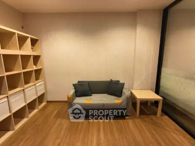Cozy living room with modern sofa, wooden shelves, and large window for natural light.