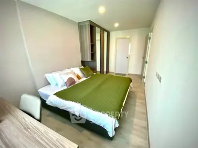 Modern bedroom with stylish decor and ample natural light, featuring a cozy bed and sleek furnishings.