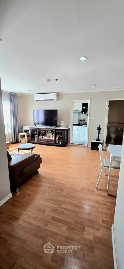 Spacious living room with wooden flooring and modern furnishings in a cozy apartment.