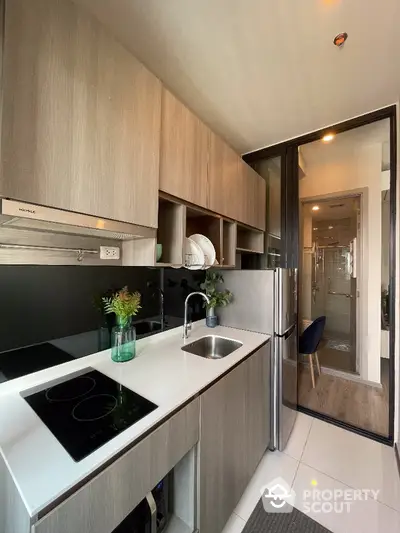 Modern kitchen with sleek cabinetry and glass backsplash in stylish apartment