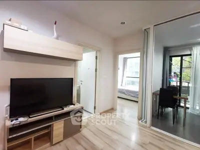 Modern apartment interior with open living area and bedroom view, featuring sleek wooden flooring and contemporary decor.