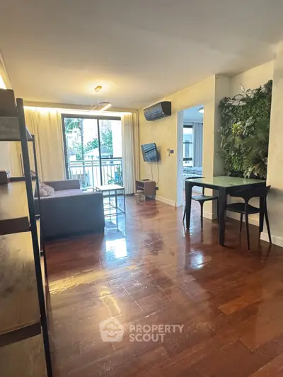 Modern living room with wooden floors, stylish furniture, and a lush green wall feature.