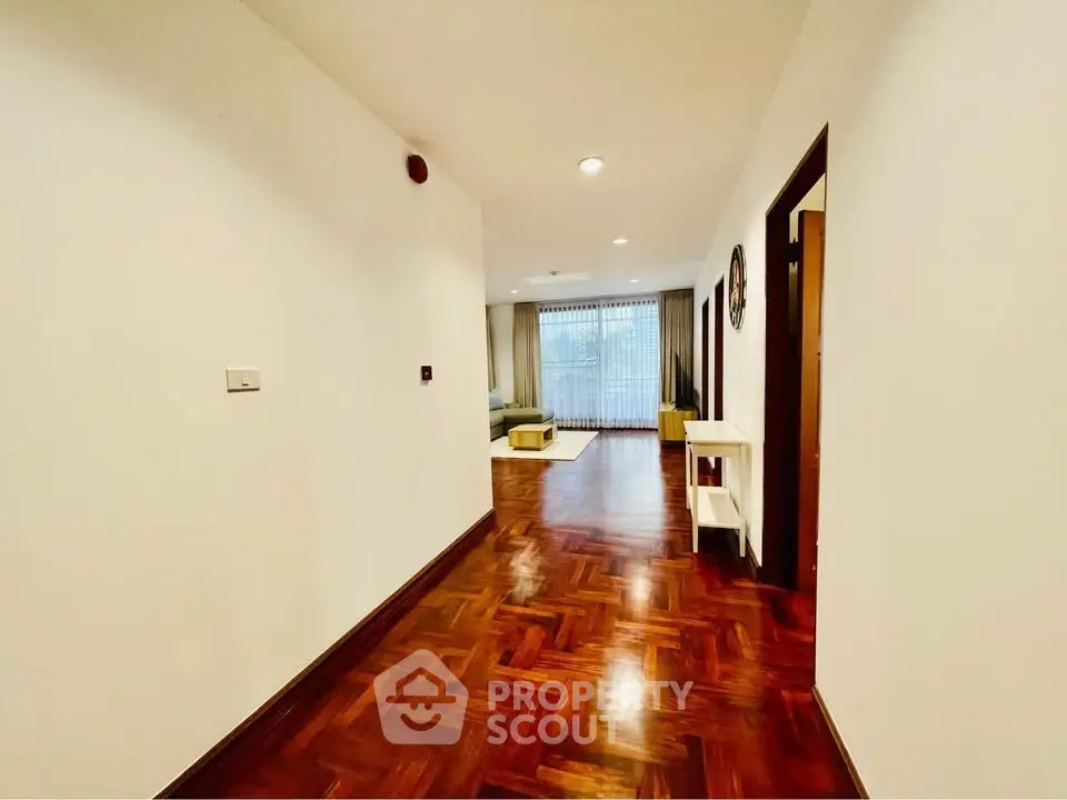 Spacious hallway leading to a bright living room with elegant wooden flooring and modern decor.