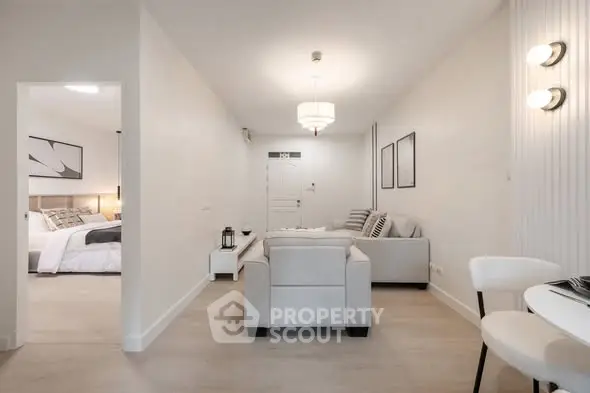 Modern living room with neutral decor and open view to bedroom