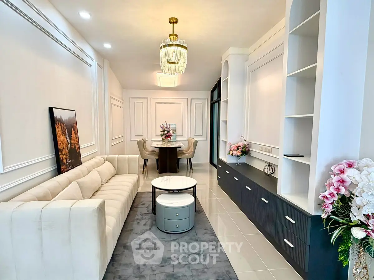 Elegant living room with plush sofa, modern chandelier, and stylish decor in a contemporary apartment.