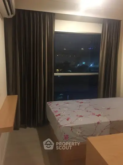 Cozy bedroom with large window and floral bedding, perfect for relaxation.