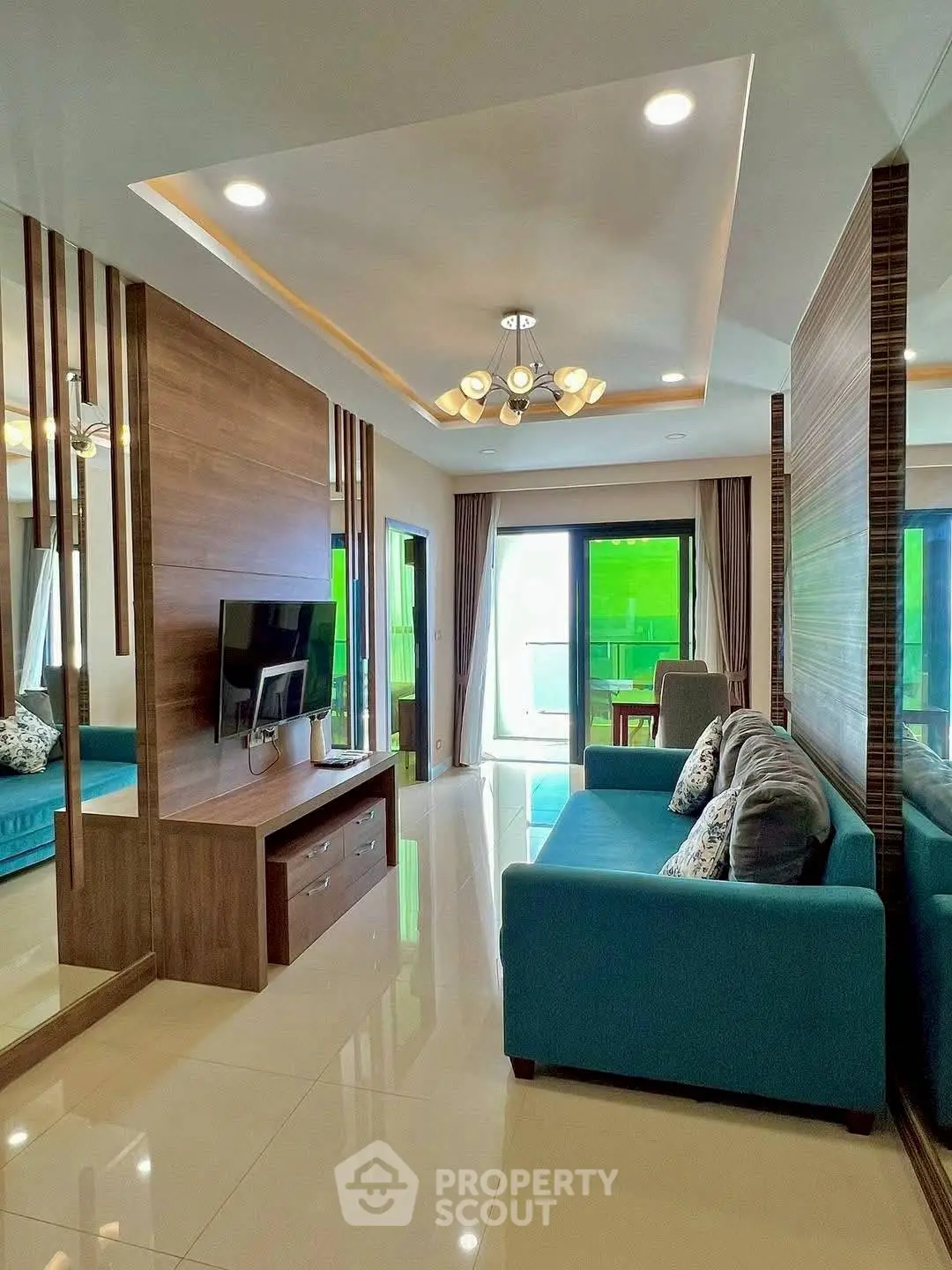 Modern living room with stylish decor and vibrant blue sofa, featuring a sleek TV unit and large windows.