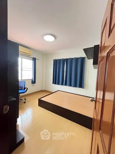 Spacious bedroom with wooden flooring and large window, perfect for natural light.