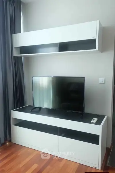 Modern living room with sleek TV stand and wall-mounted cabinet, featuring elegant wooden flooring.