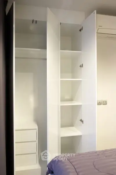 Modern bedroom with open white wardrobe and built-in storage solutions.