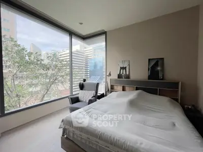 Spacious bedroom with large windows offering stunning city views, modern furnishings, and natural light.