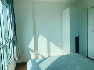 Bright bedroom with large window and modern wardrobe in a high-rise apartment.