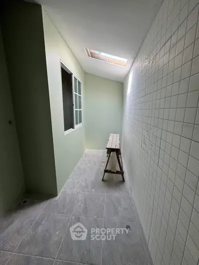 Spacious tiled balcony with skylight and window, ideal for relaxation.