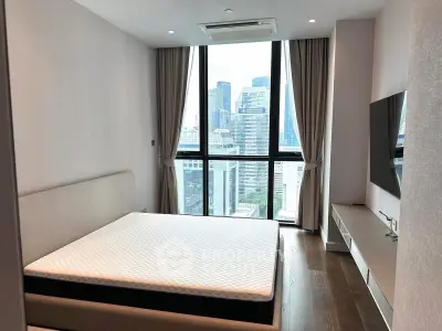 Modern bedroom with city view, featuring large windows and sleek furnishings.