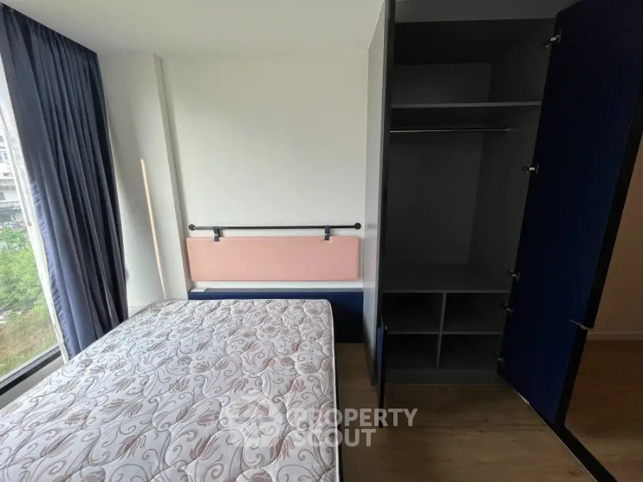 Modern bedroom with large window and built-in wardrobe, offering ample natural light and storage space.