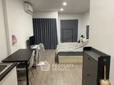 Modern studio apartment with cozy bedroom and dining area, featuring sleek furniture and neutral decor.