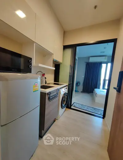 Modern compact kitchen with appliances and view into cozy bedroom