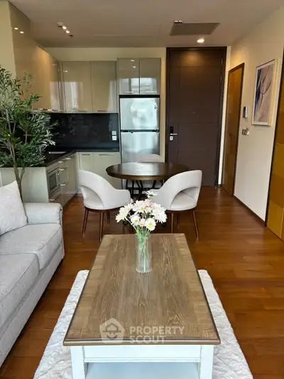 Modern living room with open kitchen, stylish furniture, and wooden flooring in a cozy apartment.