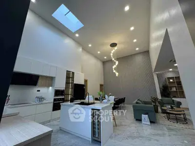 Luxurious modern kitchen with high ceiling and skylight, open layout to dining and living area.