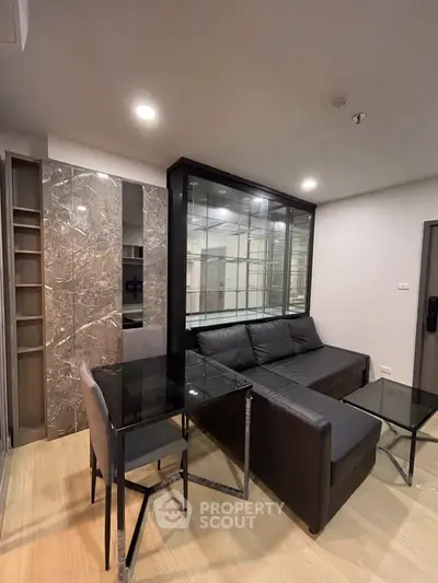 Modern living room with sleek black sofa and glass dining table in stylish apartment.