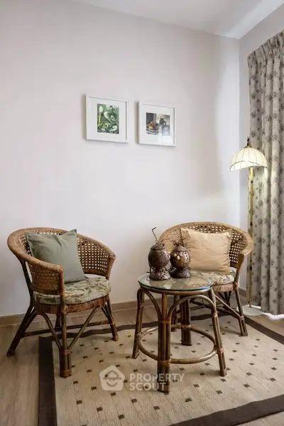 Cozy living room with wicker chairs and glass-top table, perfect for relaxation.