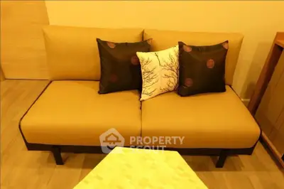 Stylish living room with modern beige sofa and decorative pillows, perfect for cozy relaxation.