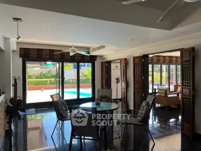 Luxurious open-plan living room with pool view and elegant dining area, perfect for entertaining.