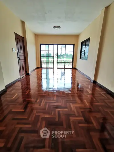Spacious room with polished wooden floors and large windows offering natural light