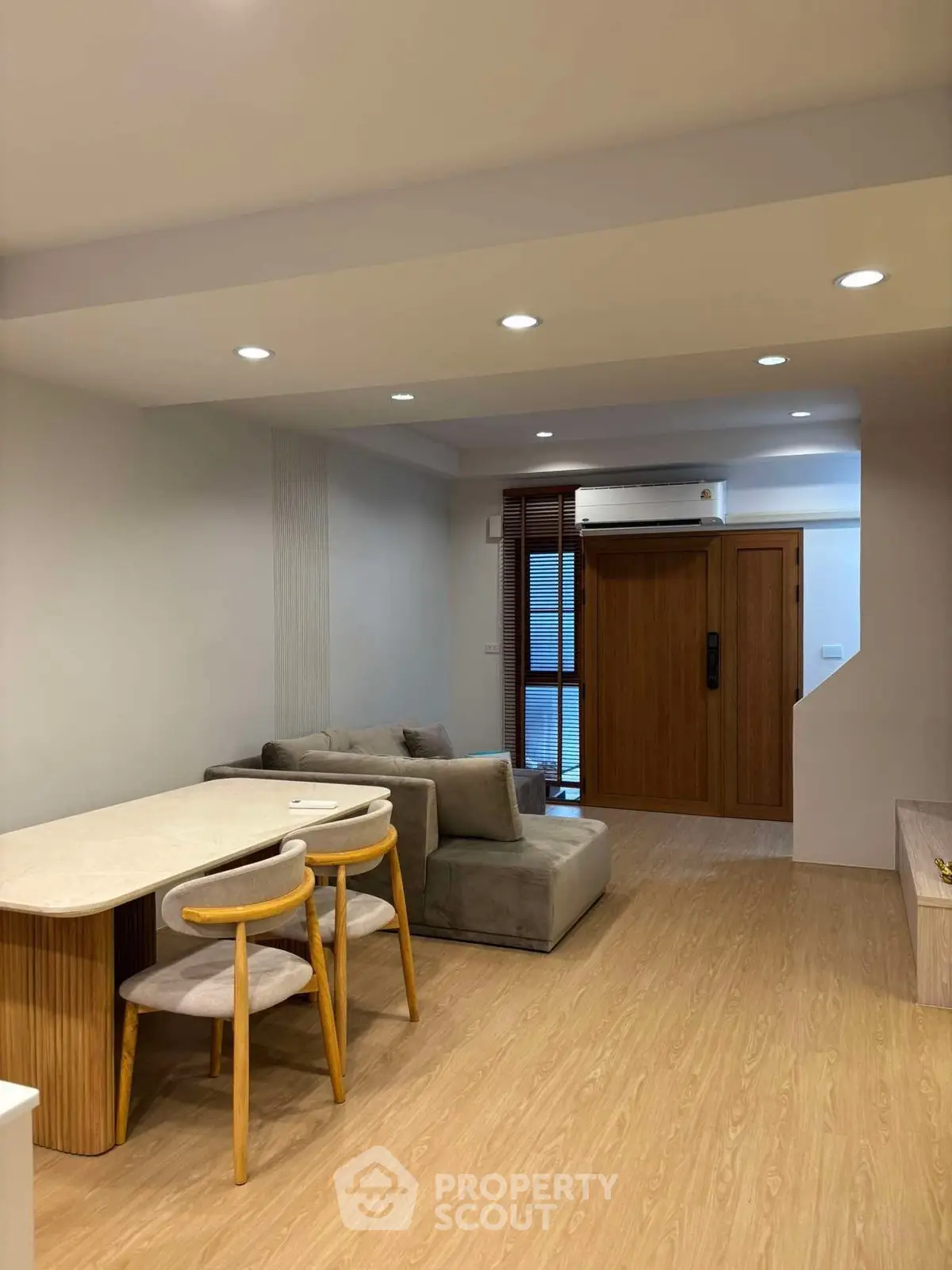 Modern living room with cozy sofa and dining area, featuring wooden flooring and ambient lighting.