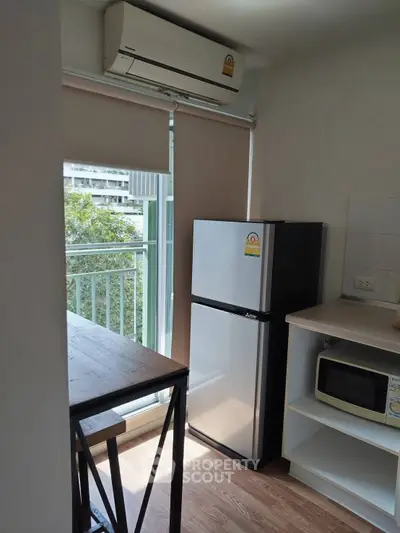 Modern kitchen with fridge, microwave, and balcony view in a stylish apartment.