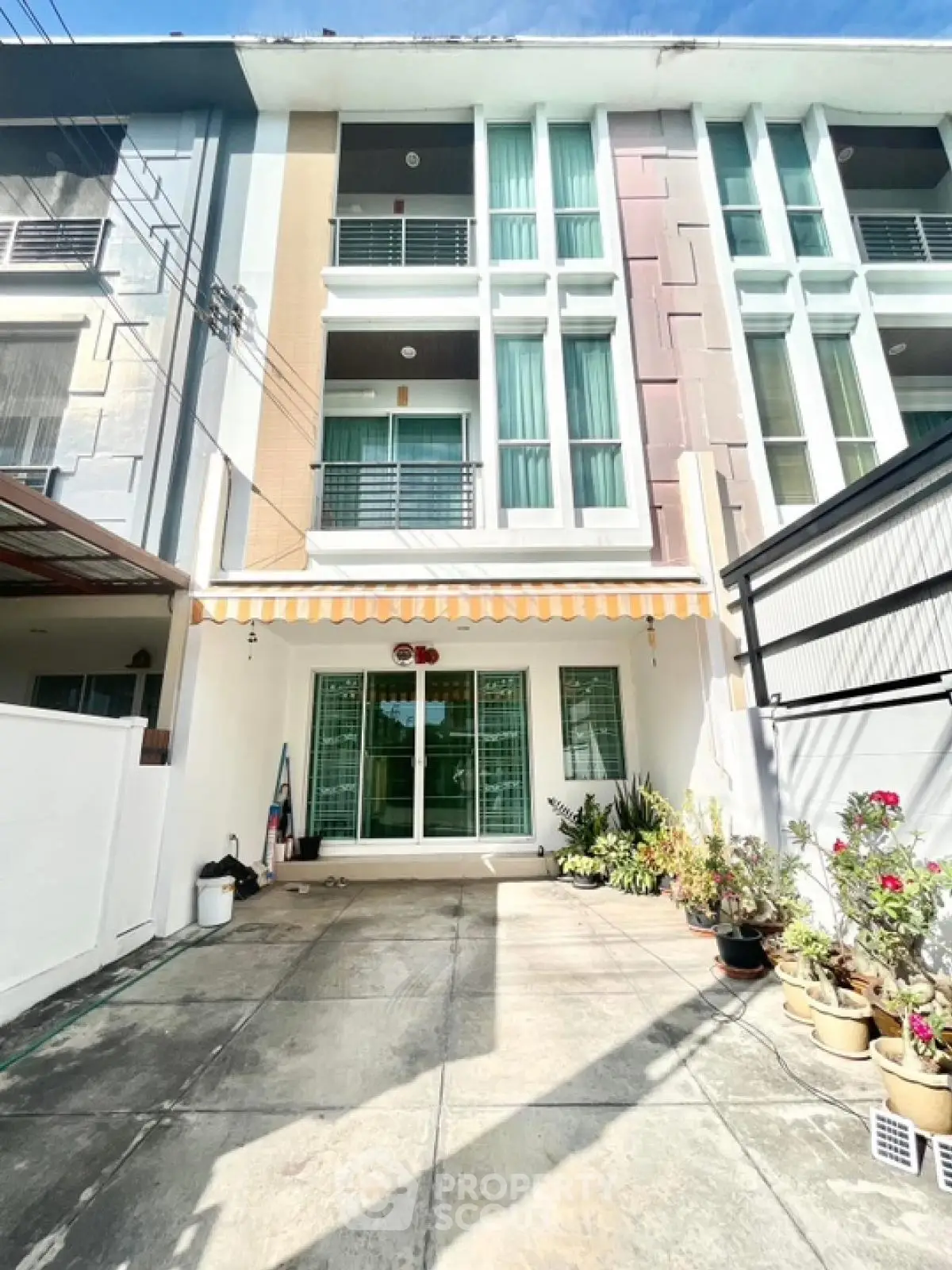 Modern three-story townhouse with spacious driveway and potted plants