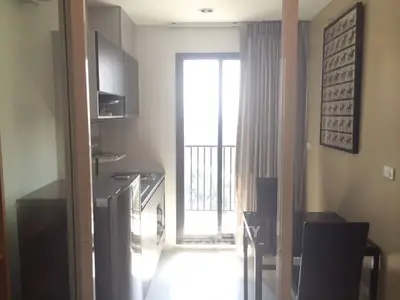 Modern kitchen with sleek appliances and dining area leading to a balcony with natural light.