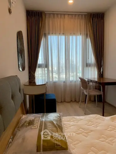 Cozy bedroom with large window and study desk, perfect for relaxation and productivity.