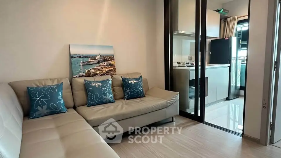 Modern living room with sleek kitchen, featuring a cozy sofa and stylish decor in a contemporary apartment.
