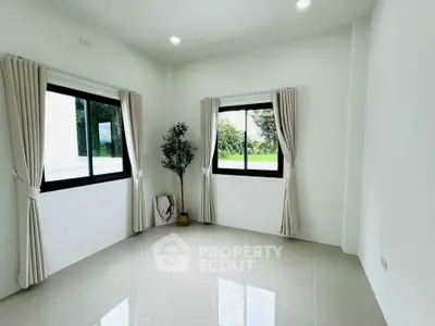 Bright and spacious room with large windows and elegant curtains, perfect for a cozy living space.