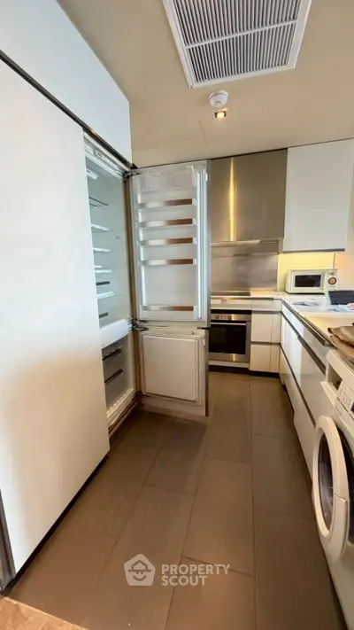 Modern kitchen with sleek appliances and open fridge in a stylish apartment.
