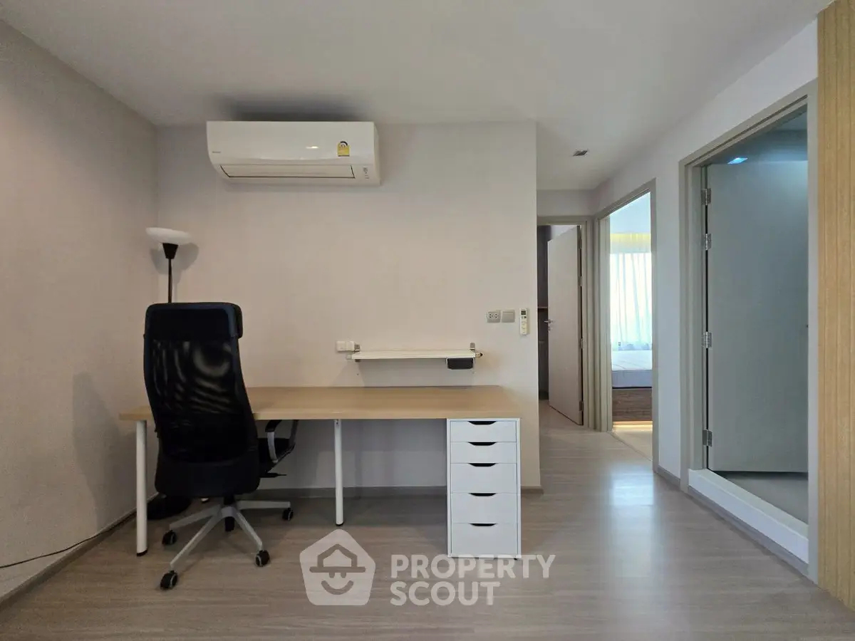 Modern study room with desk, chair, and air conditioning in a bright apartment.