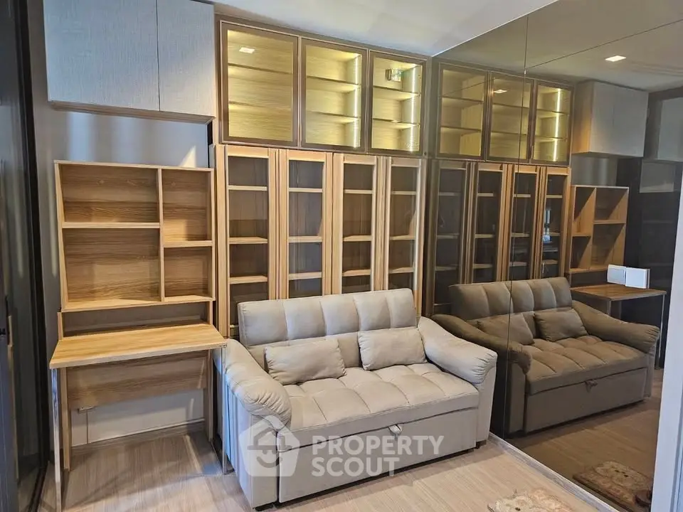 Modern living room with stylish shelving and comfortable sofa, featuring mirrored wall for spacious feel.