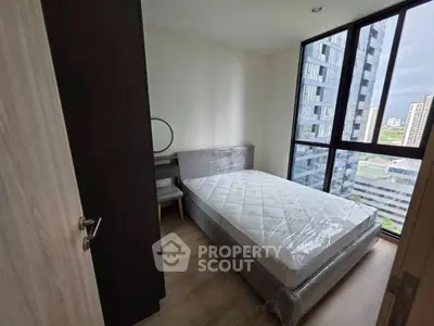 Modern bedroom with large windows and city view in high-rise apartment