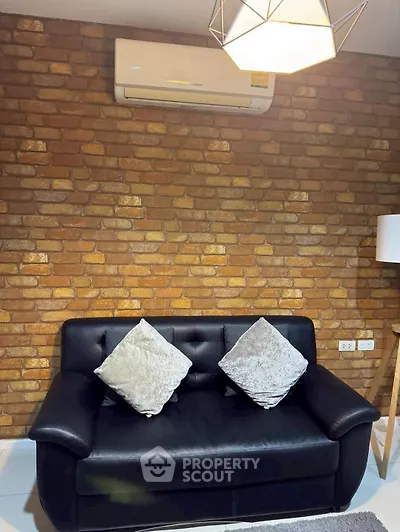 Cozy living room with black leather sofa and brick accent wall
