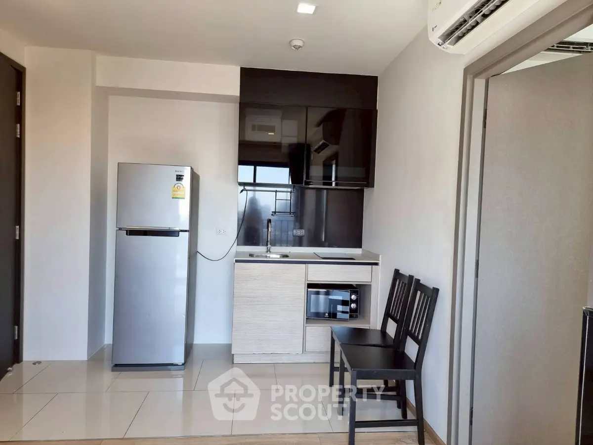 Modern compact kitchen with sleek appliances and dining area in a stylish apartment.
